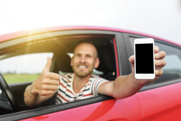 Man in car showing smart phone.