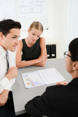 Wall Mural - three young business people at business meeting looking and discussing data documents in office