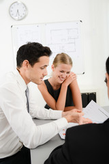 Wall Mural - three young business people at business meeting looking and discussing data documents in office