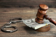 Dollar Banknotes, Handcuffs And Judge Gavel On Wood Table