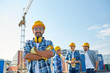 © Syda Productions - group of smiling builders in hardhats outdoors