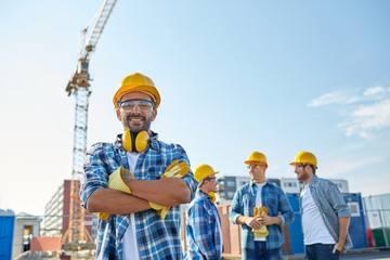 Wall Mural - group of smiling builders in hardhats outdoors