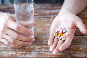 Wall Mural - close up of male hands holding pills and water