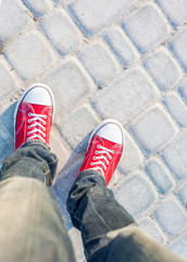 Wall Mural - young man feet in red sneakers on cobbled road