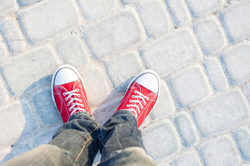 Wall Mural - young man feet in red sneakers on cobbled road