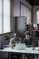 Wall Mural - African American and Caucasian man using a laptop in the office