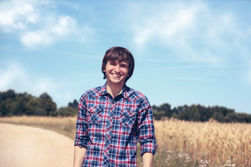 Portrait of happy handsome man with beautiful white smile on blue nature background. Happy young man. Man in the wheat field. 