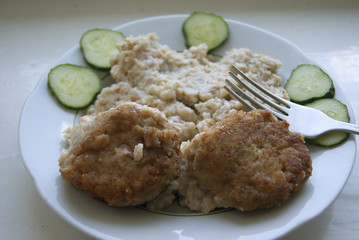 Two meatballs, with porridge and cucumbers