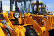© antonmatveev - Bulldozer headlight, row of huge orange powerful construction machines, tractors, excavators, focused on spotlight, blue sky and white clouds on background, selective focus