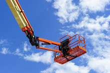 Cherry Picker Work Bucket Platform And Hydraulic Construction Cradle Of Lifting Arm Painted In Orange And Beige Colors With White Clouds And Blue Sky On Background, Heavy Industry Machinery Vehicle 