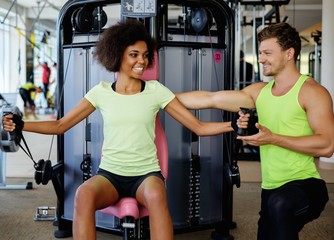 Wall Mural - Trainer explaining how to use training machine in a gym