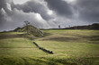 Dramatic landscape of the Yorkshire England countryside with stone wall, rocky mound and stormy clouds.