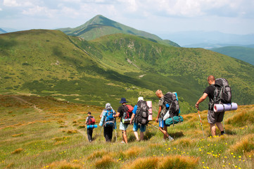 group of tourists with large backpacks are on mountain