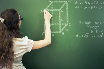 Smart student or teacher drawing mathematic formula at blackboard