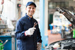 Portrait of a smiling mechanic holding a wrench