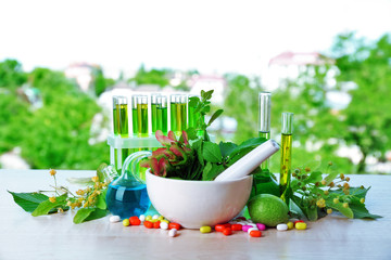Wall Mural - Herbs in mortar, test tubes and pills,  on table, on bright background