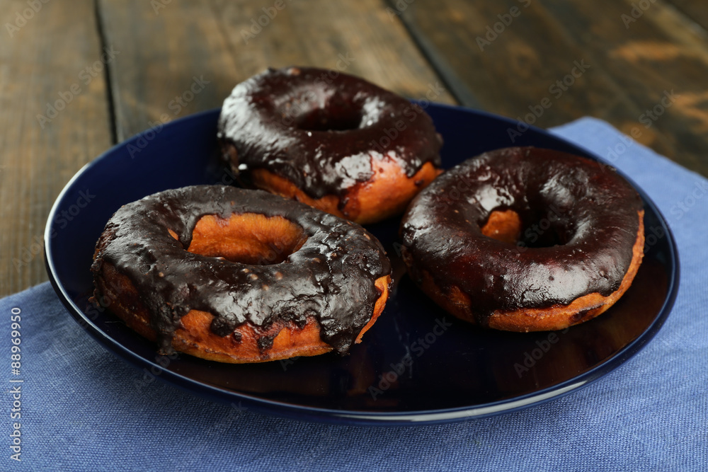 Delicious doughnuts with chocolate icing on table close up