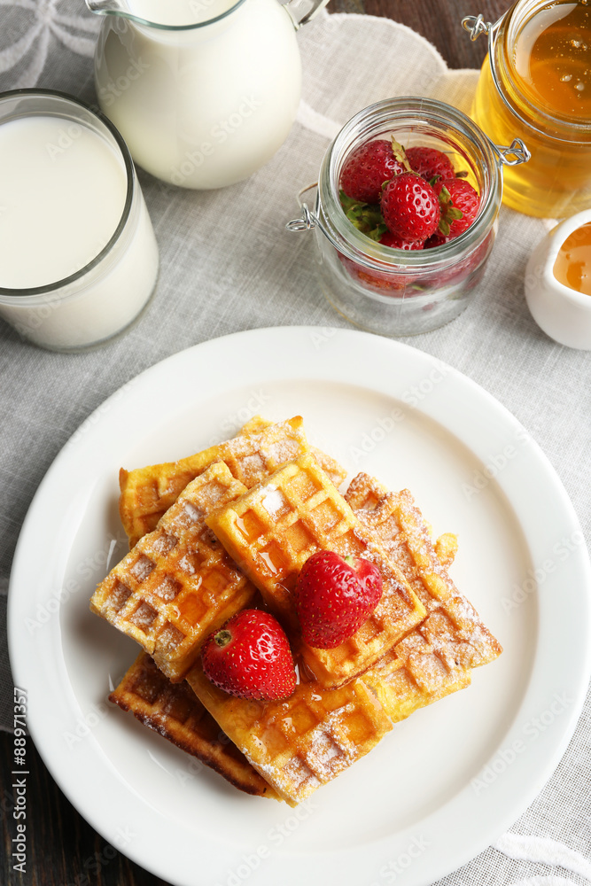 Sweet homemade waffles with strawberries  on plate, on table background