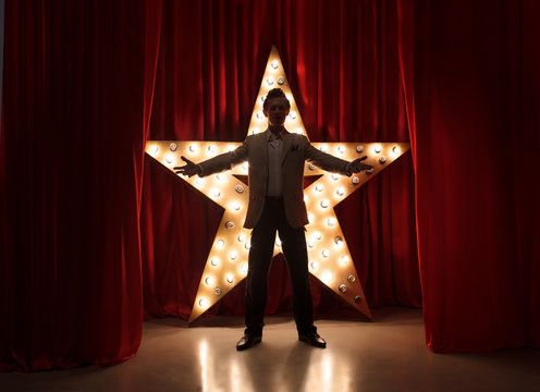 Fototapete - Man on stage with star on background