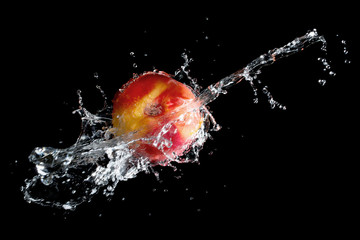 Wall Mural - Raw nectarine in water splash over black background