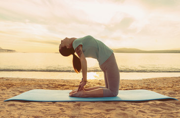 Poster - Girl doing yoga exercise on beach at sunset