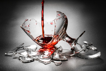 Pouring red wine on broken glass.