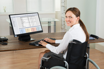 businesswoman on wheelchair using computer in office