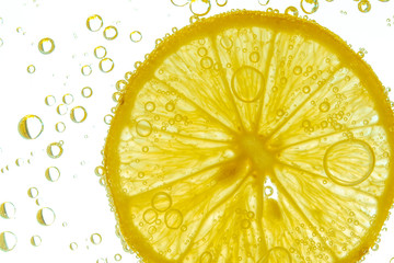 Fresh lemon slice in water with bubbles on white background