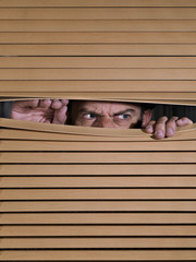 Man spying on something through venetian blinds