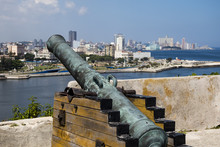 Old Canon In The Foreground Looks Over Havana Bay From The Colonial Fortaleza De San Carlos De La Cabaña Towards The Malecon And The Skyline.
