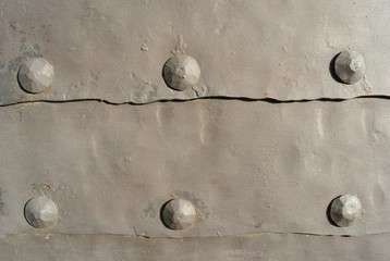 Old grey iron surface with rivets; rough, rusty texture; iron gate.