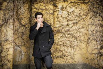 Wall Mural - Handsome young man standing against plant covered wall