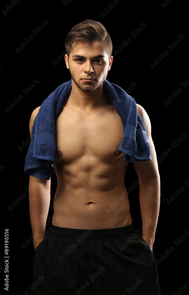 Muscle young man holding towel on dark background