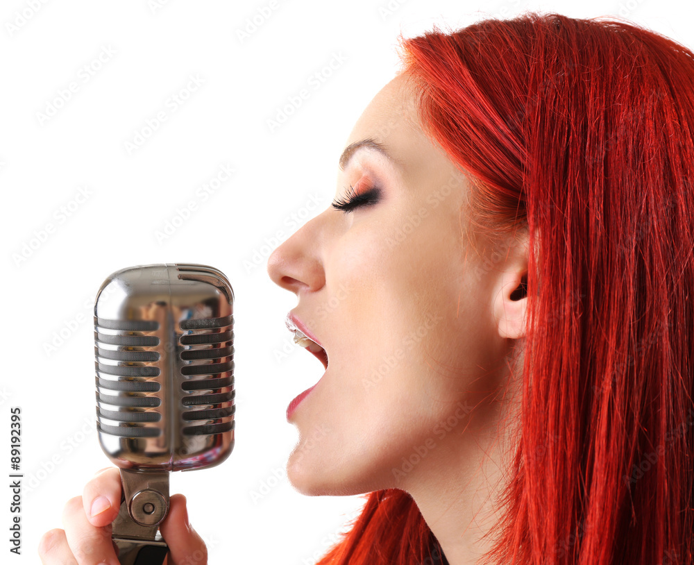 Beautiful young woman singing with microphone isolated on white