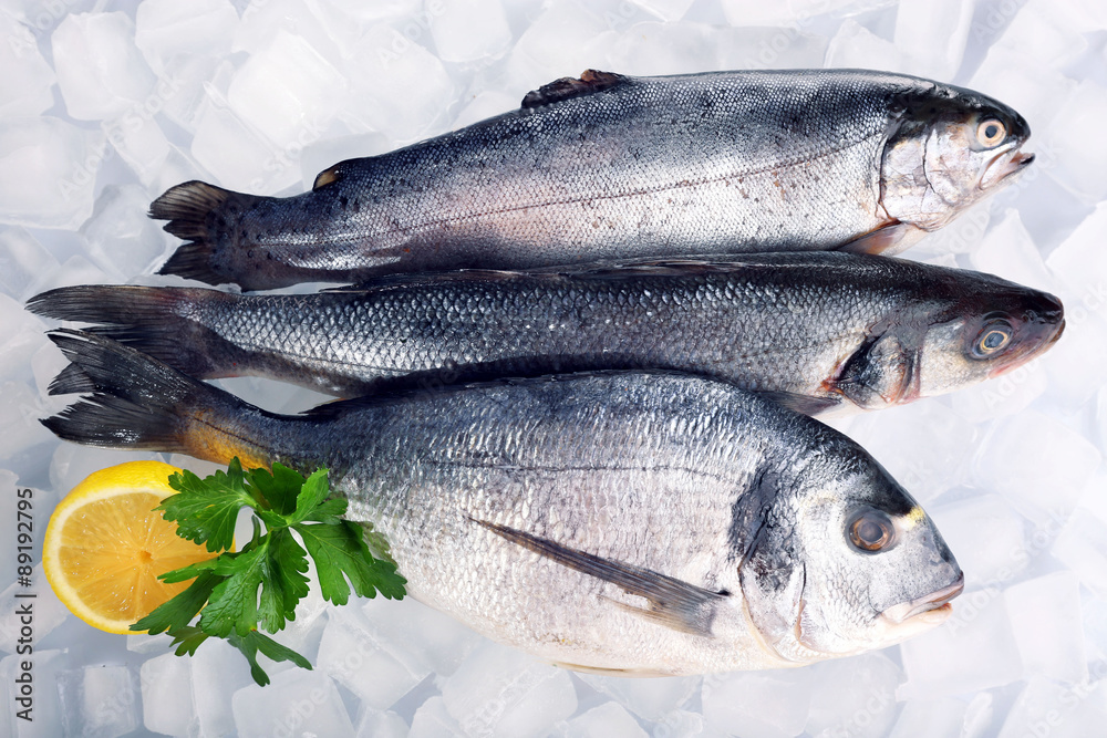 Fresh fishes with lemon on ice background