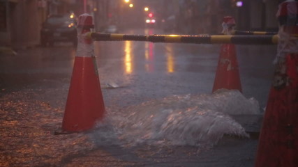 Overflowing manhole in storm with warning beacons slow motion