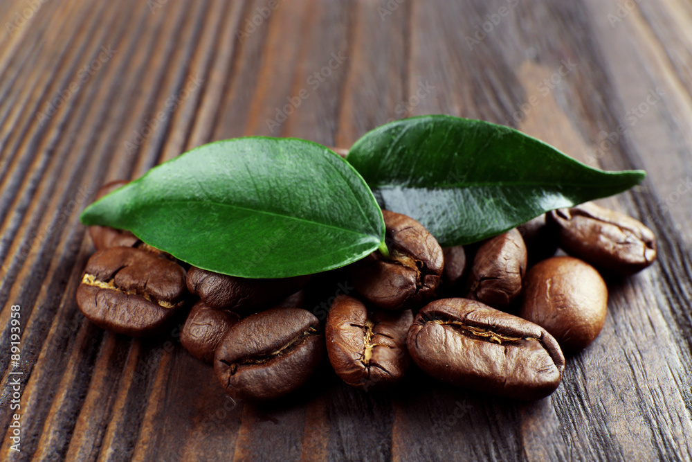 Coffee beans with leaves on wooden background
