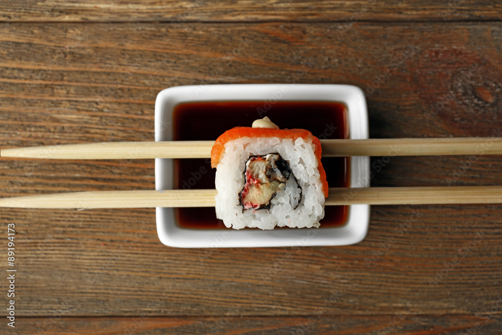Roll with sauce and sticks on wooden table close up