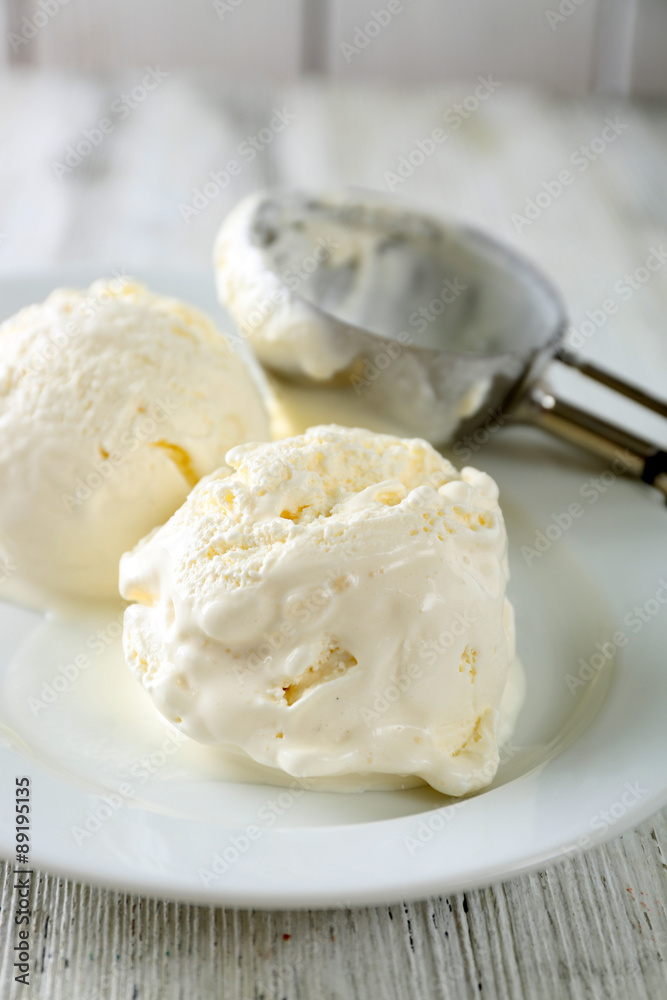 Delicious vanilla ice cream on plate, on wooden background
