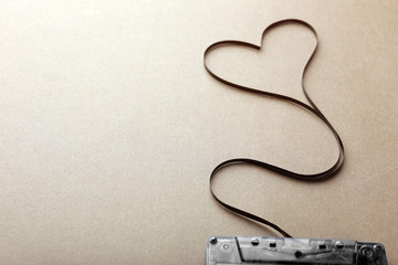 Wall Mural - Audio cassette with magnetic tape in shape of heart on brown background