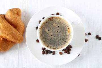 Delicious croissants with cup of coffee on white wooden backgrou