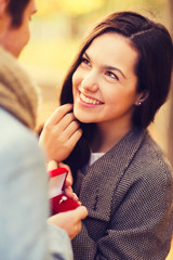 Wall Mural - close up of smiling couple with gift box in park