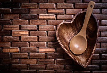 Heartshaped wood teabowl and spoon on wooden mat horizontal view