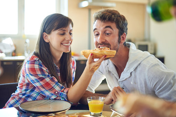 Girl feeding guy with piece of pizza