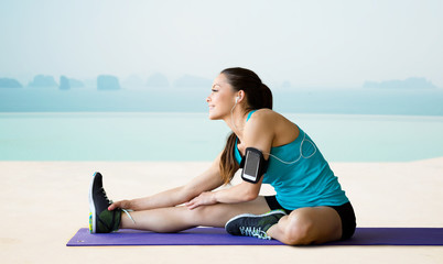 Canvas Print - smiling woman stretching leg on mat over pool