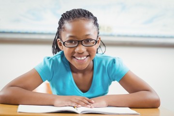 Wall Mural - Smiling pupil reading book in a classroom