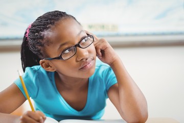 Wall Mural - Cute african american pupil daydreaming at her desk in a classroom