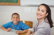 © WavebreakMediaMicro - Smiling teacher and her pupil sitting at desk