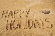 The Words Happy Holidays Written In The Sand On The Beach
