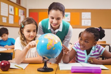 Wall Mural - Teacher and pupils looking at globe